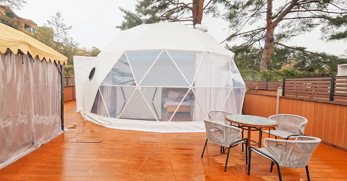 A white dome-shaped glamping tent on a wooden deck.