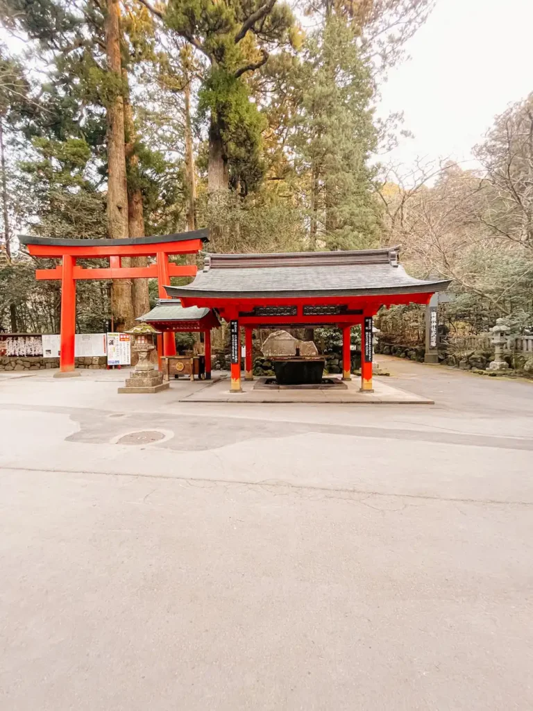 A red torii gate and shrine in the forest.