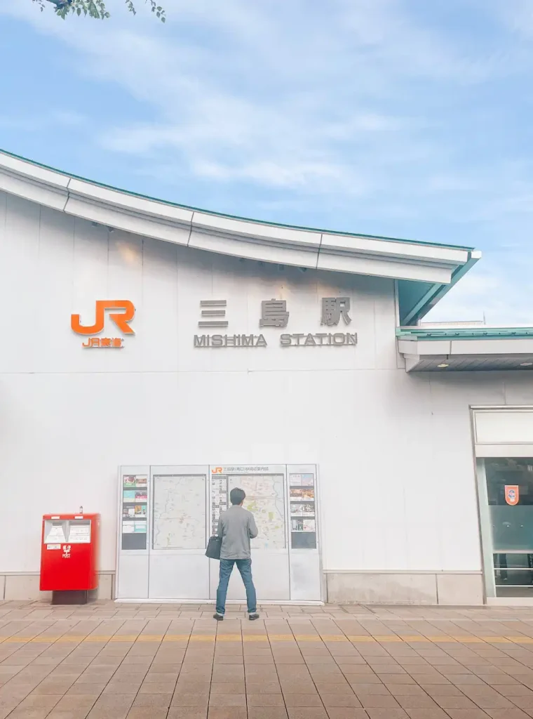 A man standing in front of JR Mishima Train Station in Japan