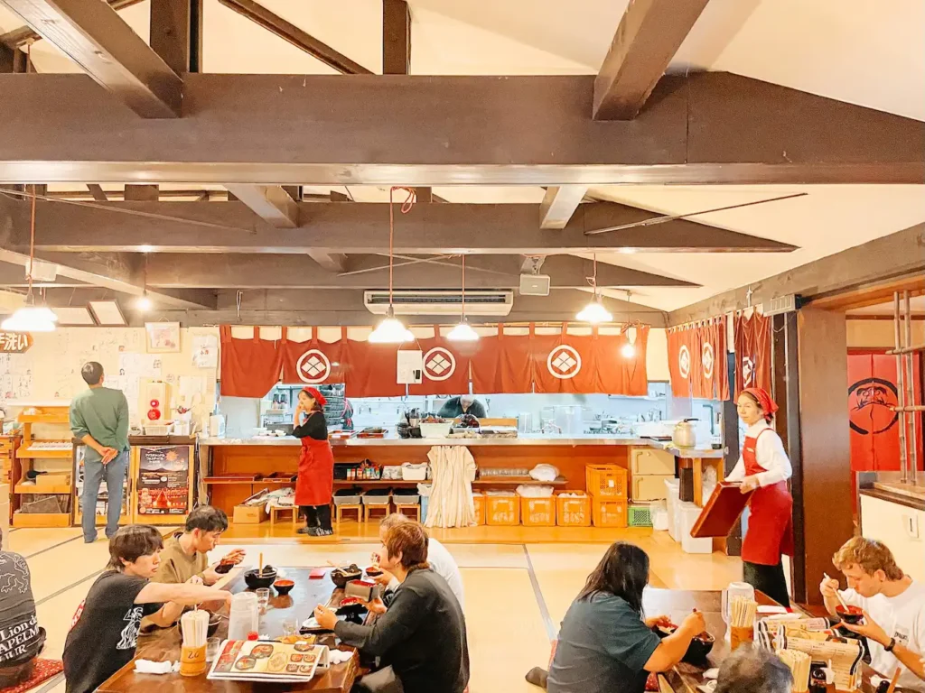 The interior of a Japanese restaurant with diners sitting on tatami mats.