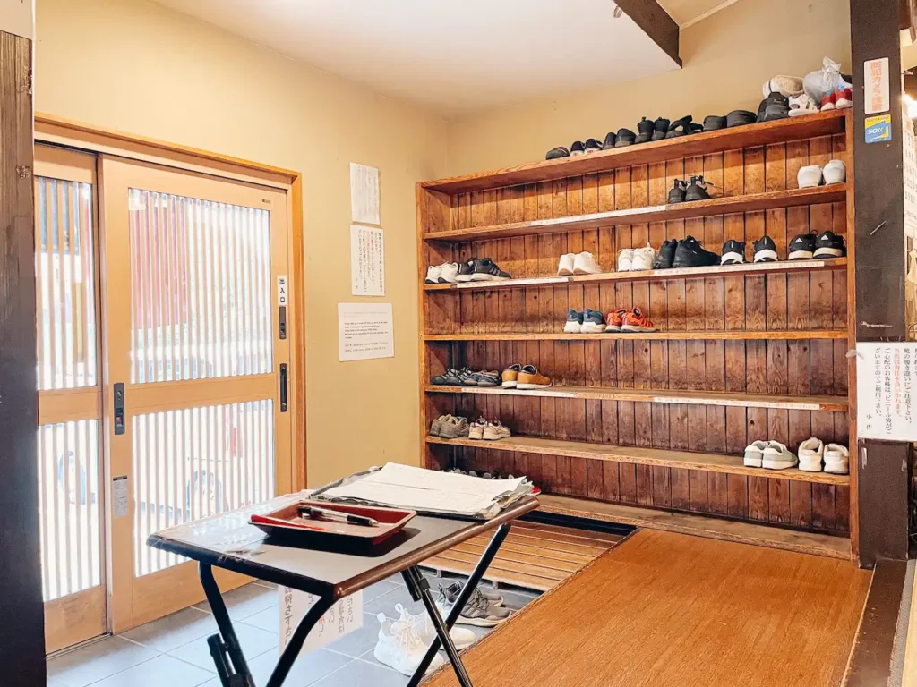 The interior of a Japanese restaurant with shoes at the front of the shop.