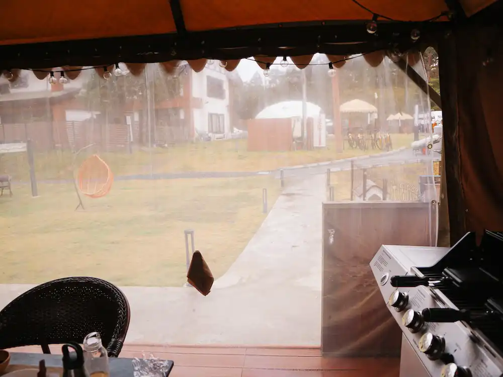 A barbecue grill in an enclosed tent on a rainy day
