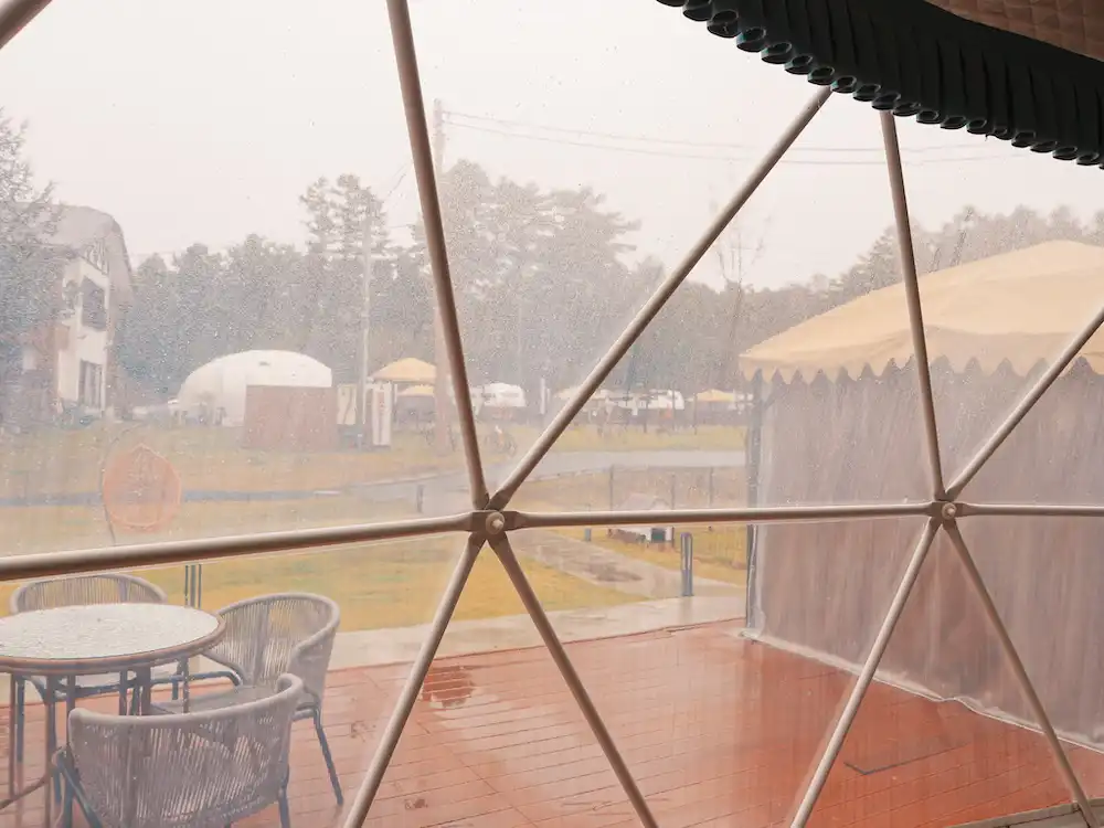 The window of a glamping tent on a rainy day